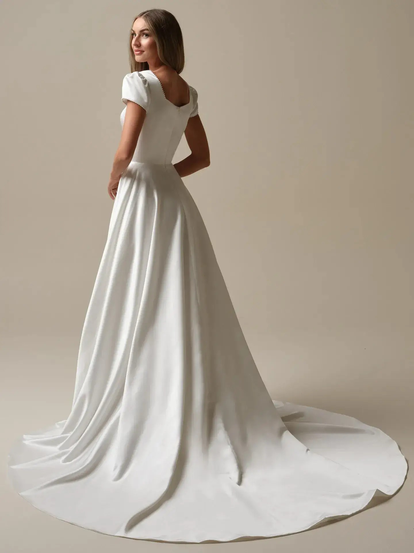 Model is wearing a satin wedding dress with puff sleeves by rebecca ingram