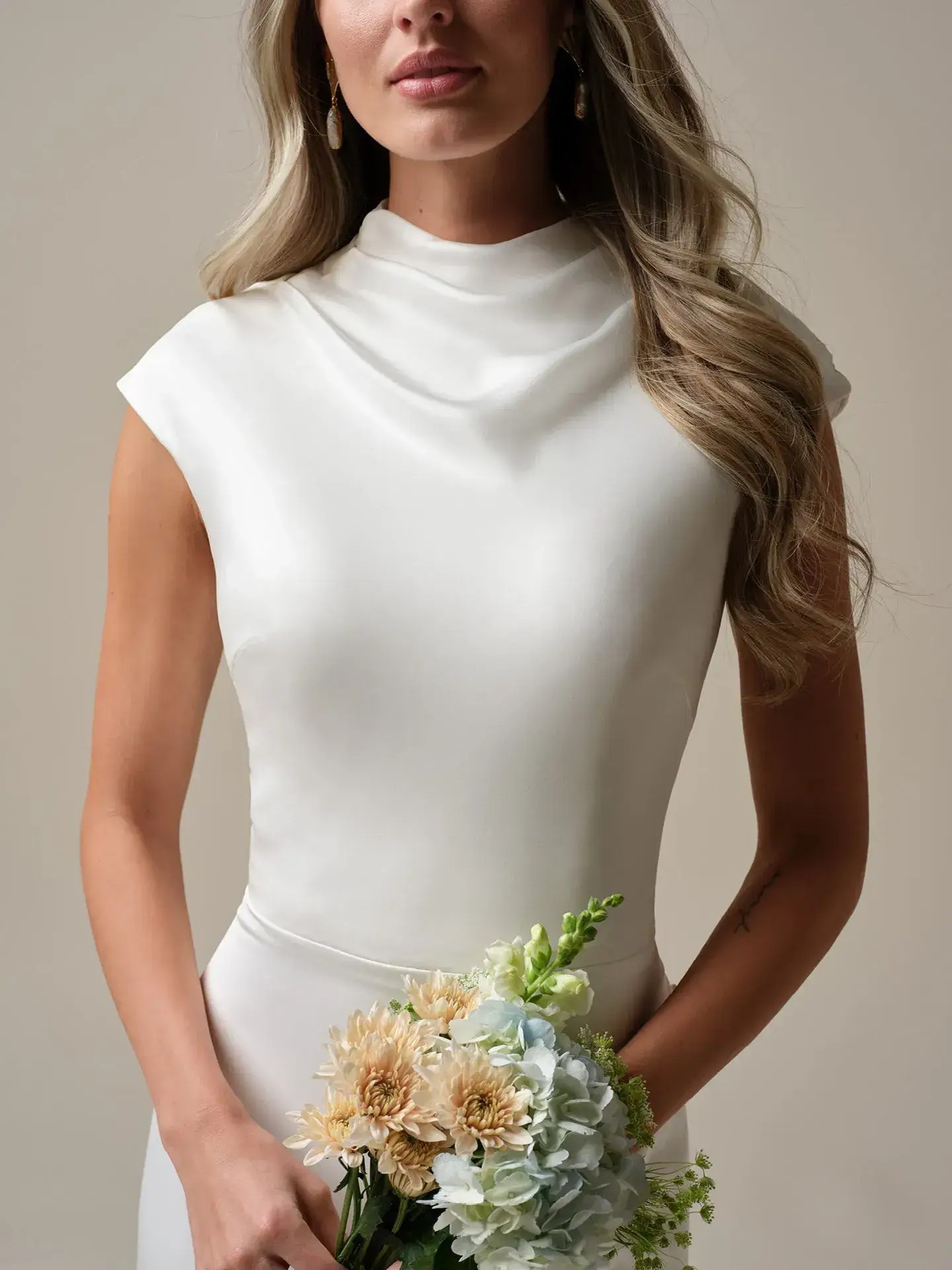 Model is wearing a sheath bridal gown with a cowl neckline by rebecca ingram