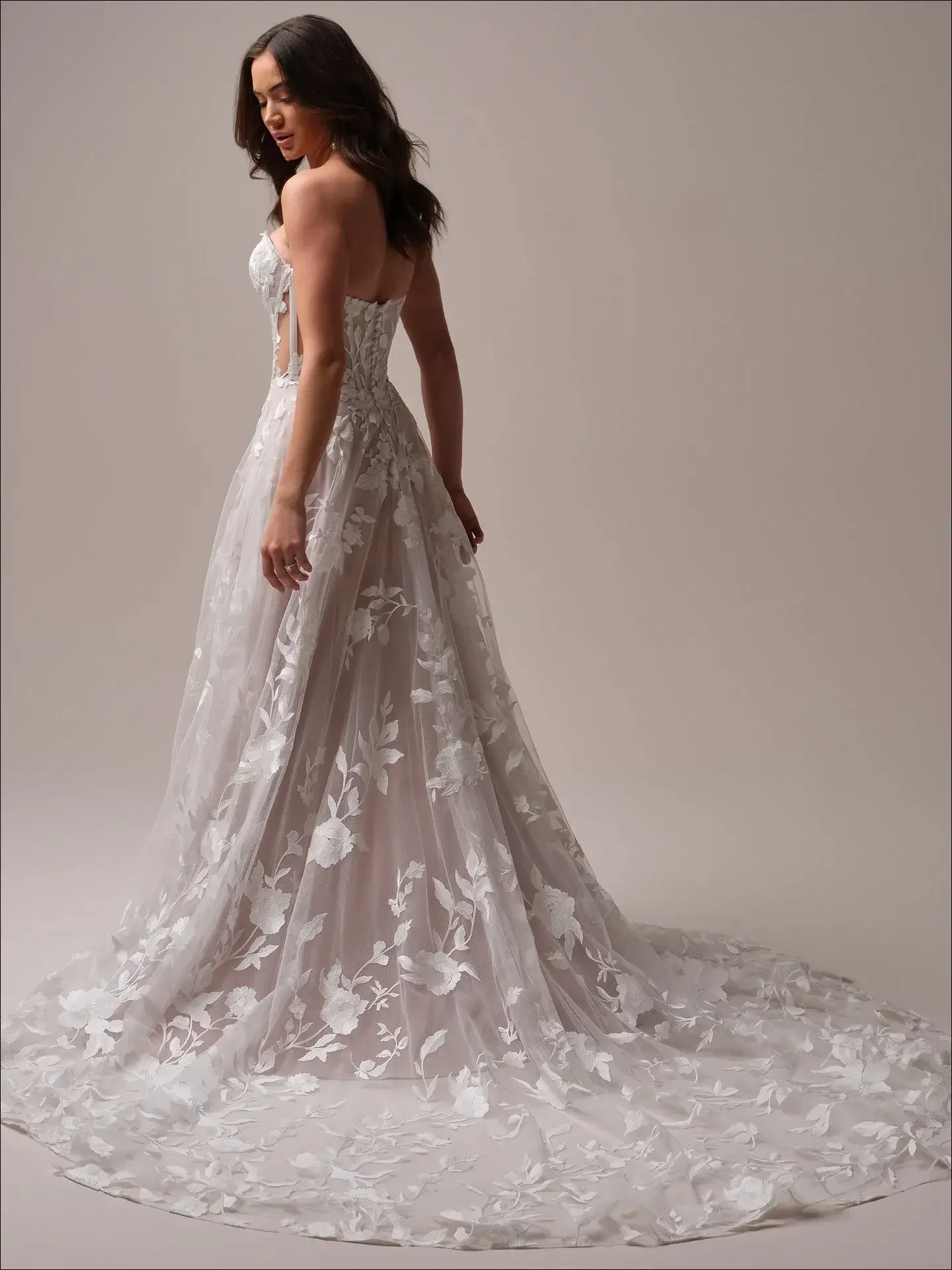 Model is wearing a floral-inspired A-line wedding gown with illusion panels and an off-the-shoulder neckline.