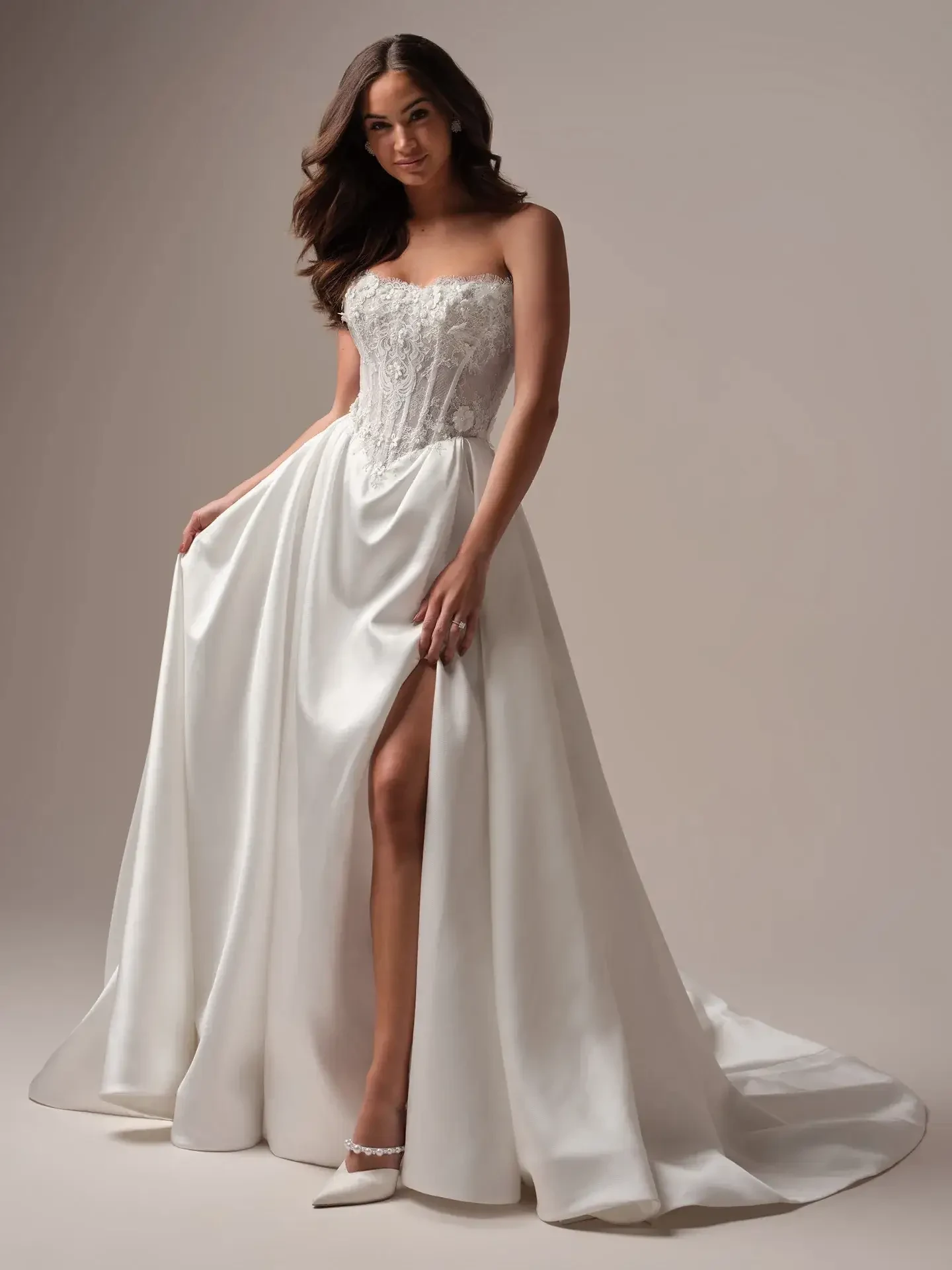 Model is wearing an off-the-shoulder lace A-line wedding gown with long sleeves, a high slit, and a sophisticated silhouette.