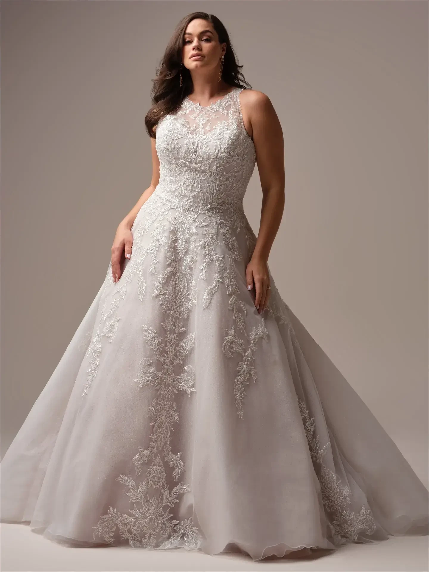 Model is wearing a halter-neck A-line wedding gown with shimmering tulle, beaded lace, an illusion back, and pockets.