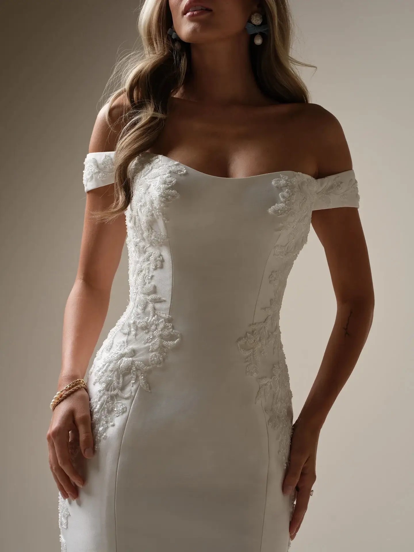 Model is wearing an off the shoulder fit and flare wedding dress by maggie sottero