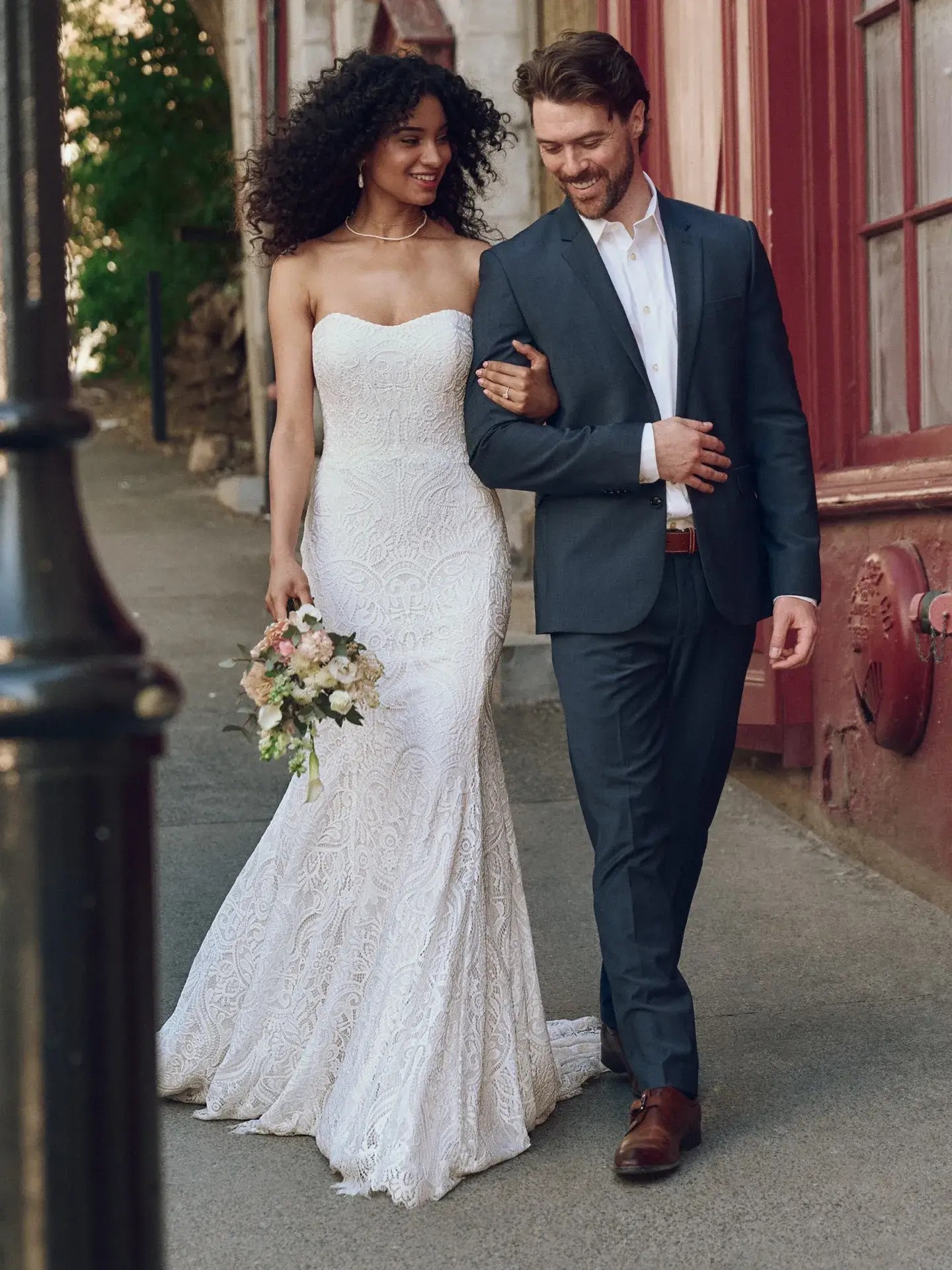 Model is wearing a lace fit and flare strapless bridal gown by rebecca ingram 